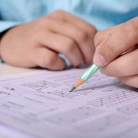close up of someone's hands filling in a scantron for an exam