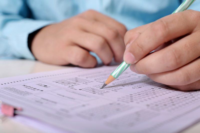 close up of someone's hands filling in a scantron for an exam